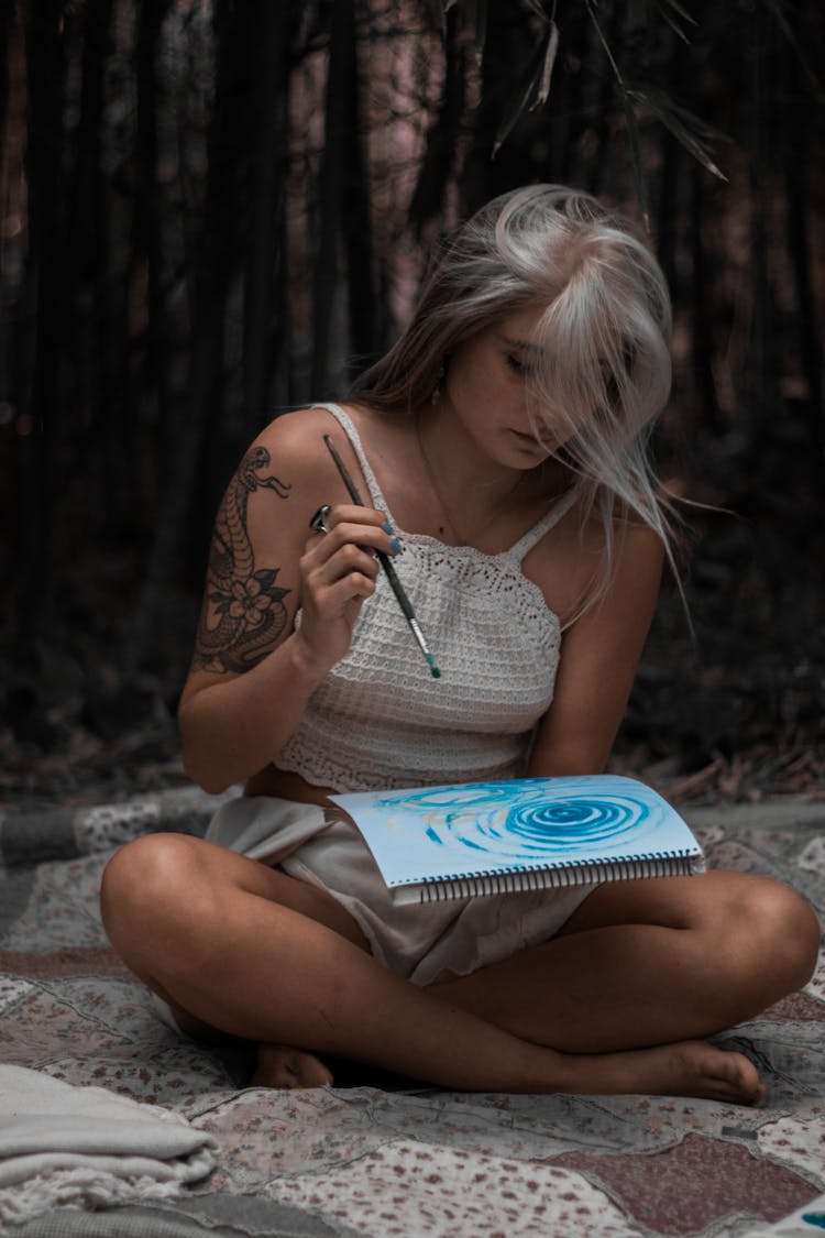 Woman With White Hair And Tattoo Painting In A Forest