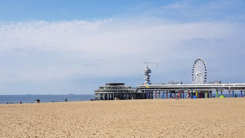 Free Scenic view of Scheveningen Pier in Den Haag with Ferris wheel and sandy beach on a sunny summer day. Stock Photo