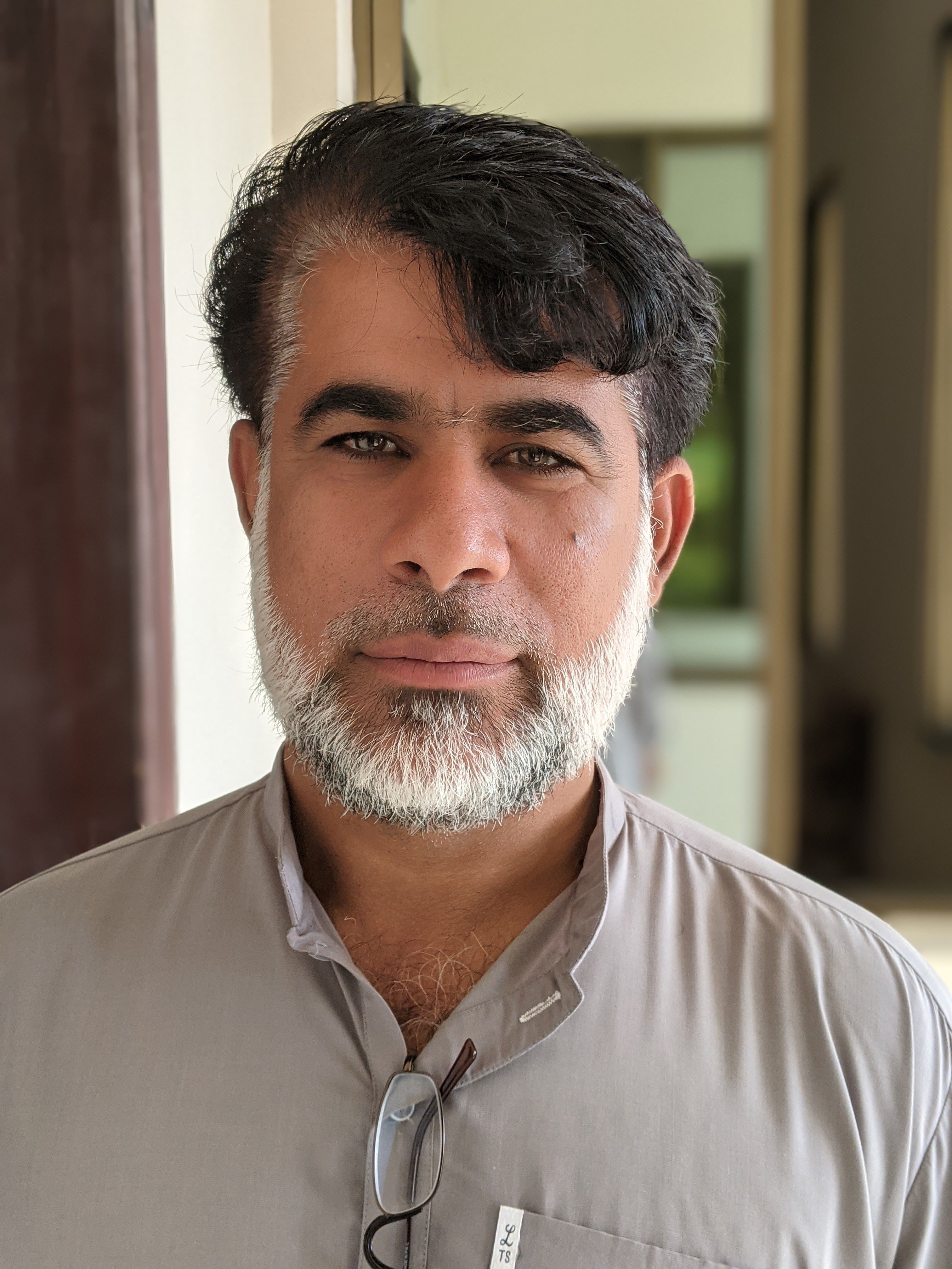 Close-up portrait of a mature Asian man with a beard in an indoor setting, conveying calmness and thoughtfulness.