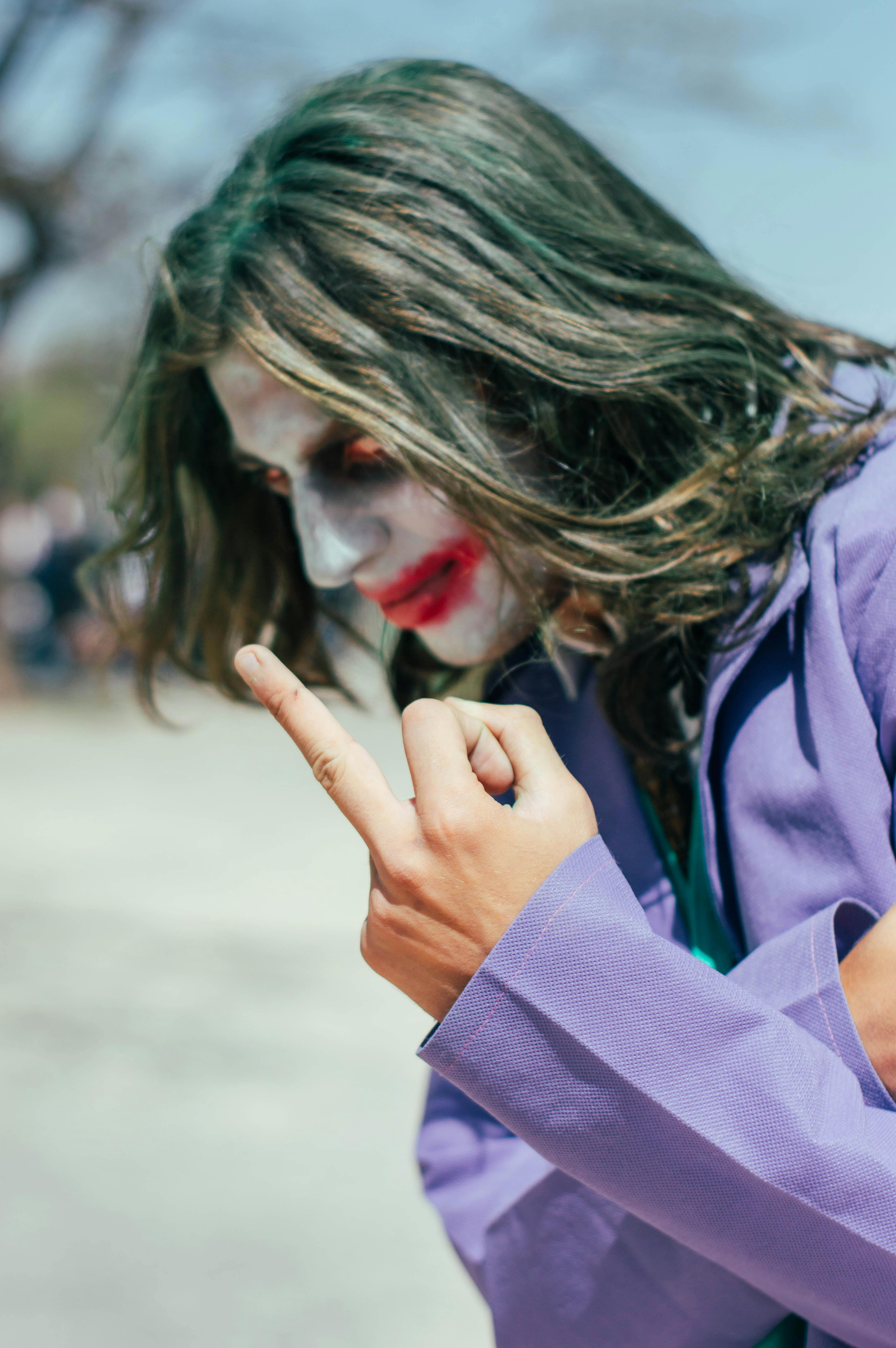 Free A person in Joker cosplay with painted face and gesture in an outdoor setting. Stock Photo