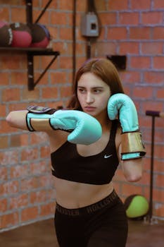 Focused young woman practicing boxing in a Mexico City gym, wearing sports clothing and boxing gloves.