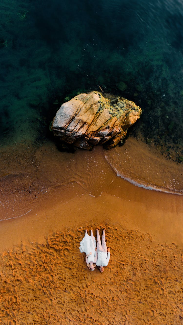 Couple Lying On Beach Near Sea