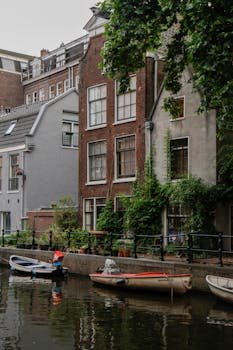 Picturesque canal houses in Amsterdam with boats docked along serene waterway.
