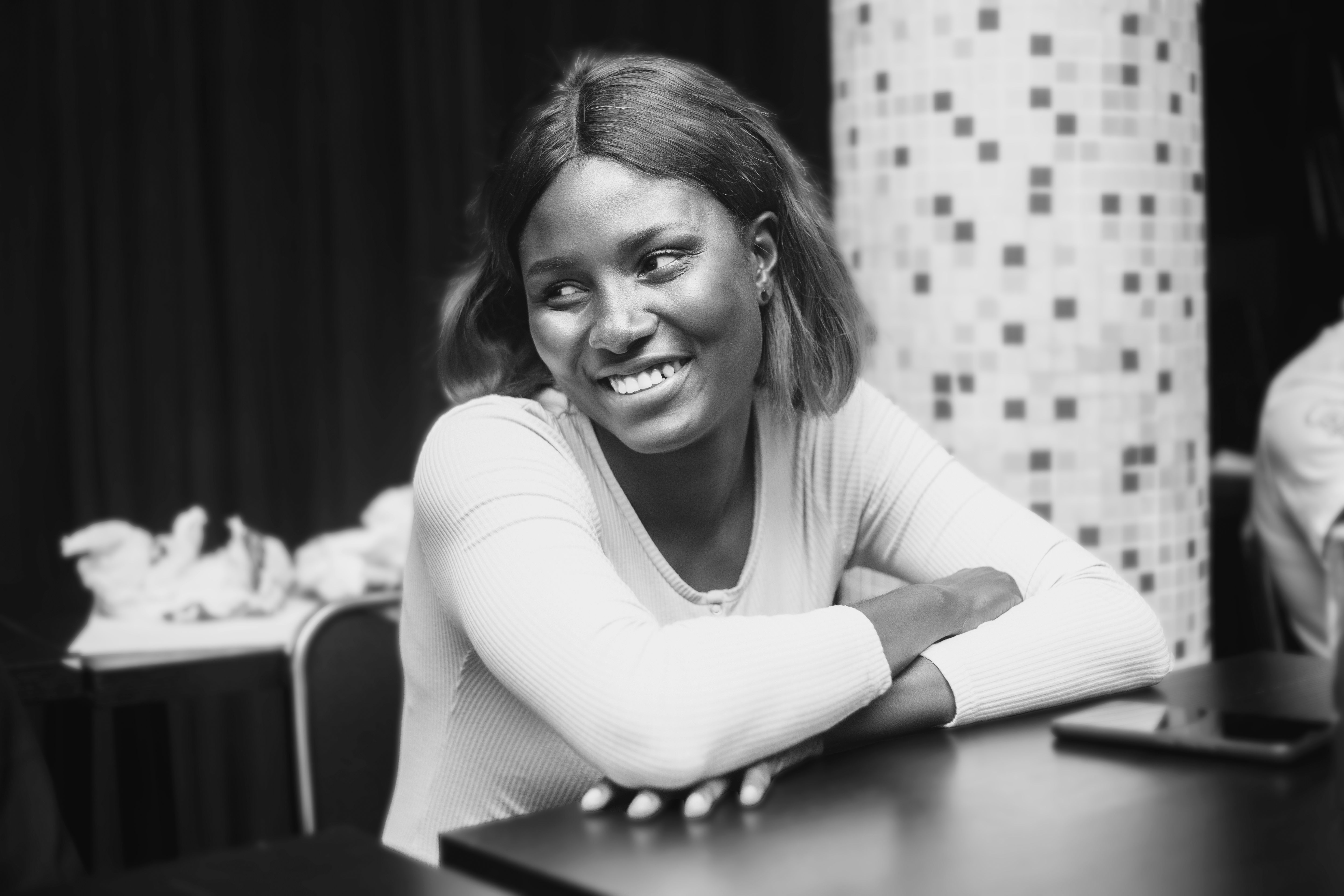 Young Woman Sitting at a Table and Smiling · Free Stock Photo