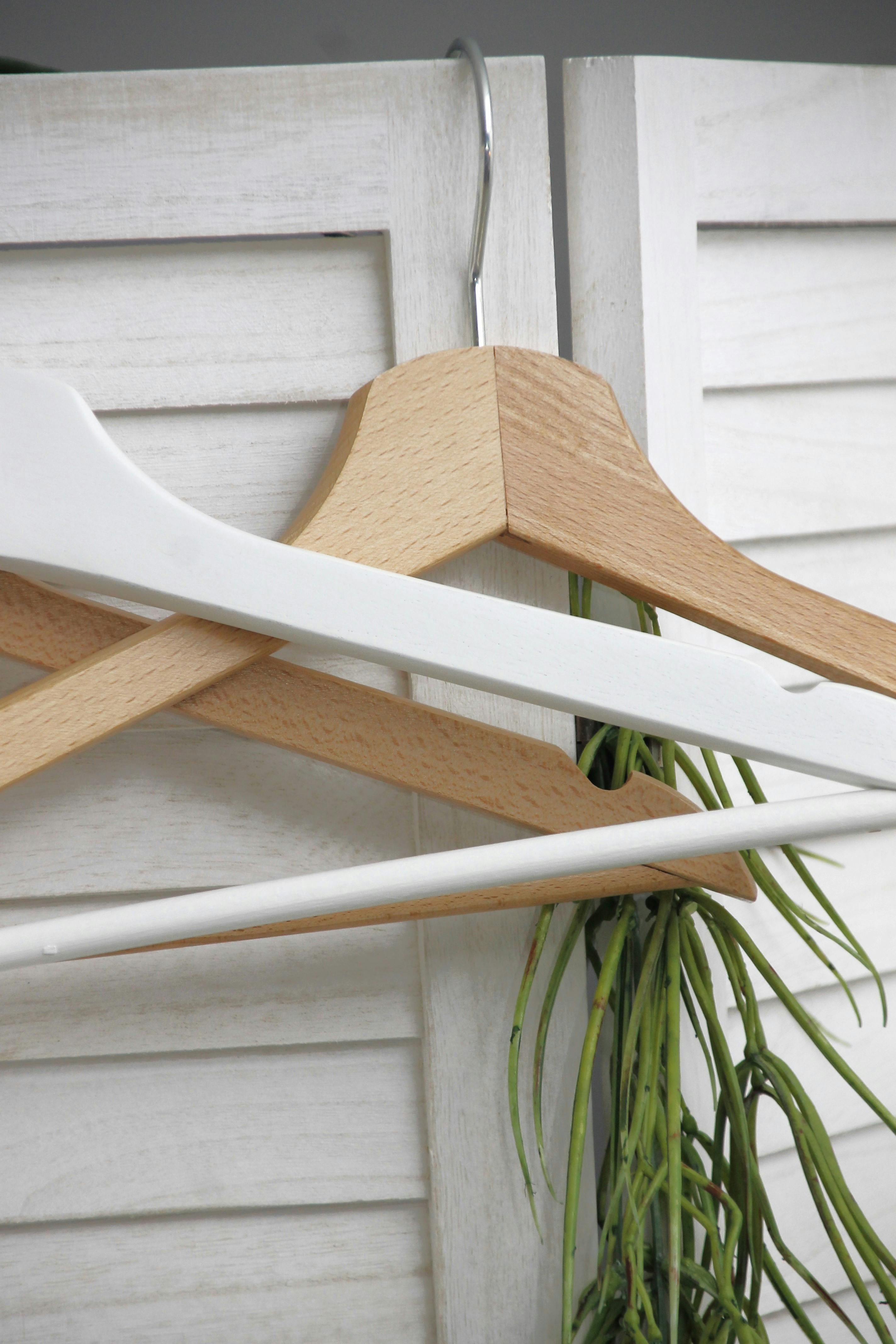 Stylish wooden hangers on a white screen, showcasing minimalist interior design.
