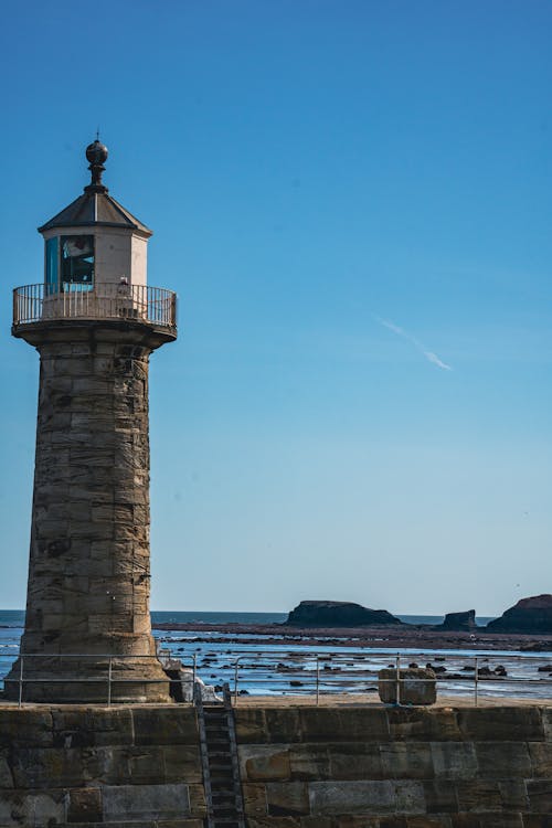 A Lighthouse Near the Body of Water Under the Blue Sky