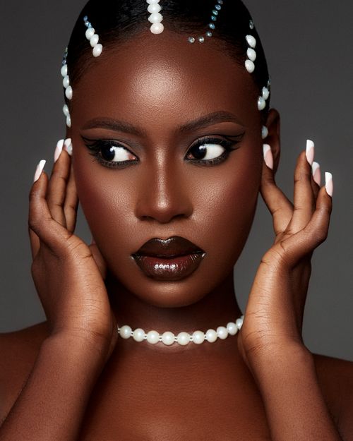 Free Glamorous studio portrait of a woman adorned with pearl jewelry and bold makeup. Stock Photo