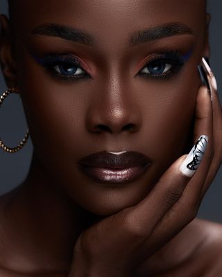 Beautiful close-up portrait showcasing bold eye makeup and fashion nail art.