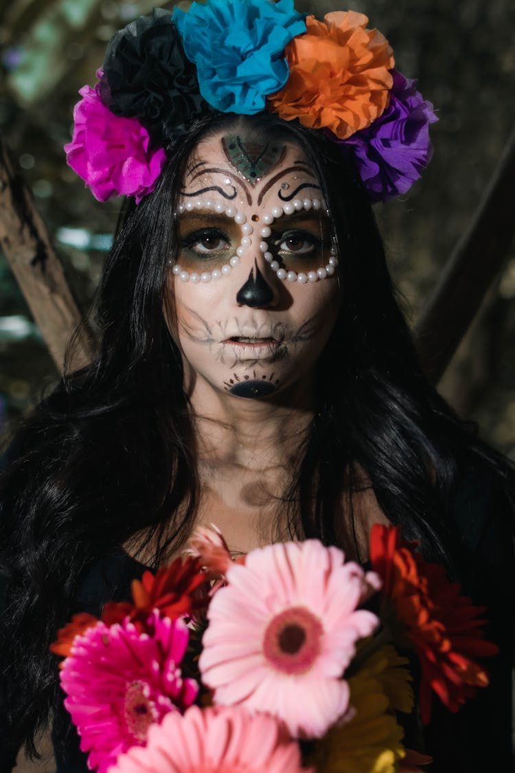 Portrait Of A Woman With Death Festival Mask And Wreath Holding Pink Gerberas