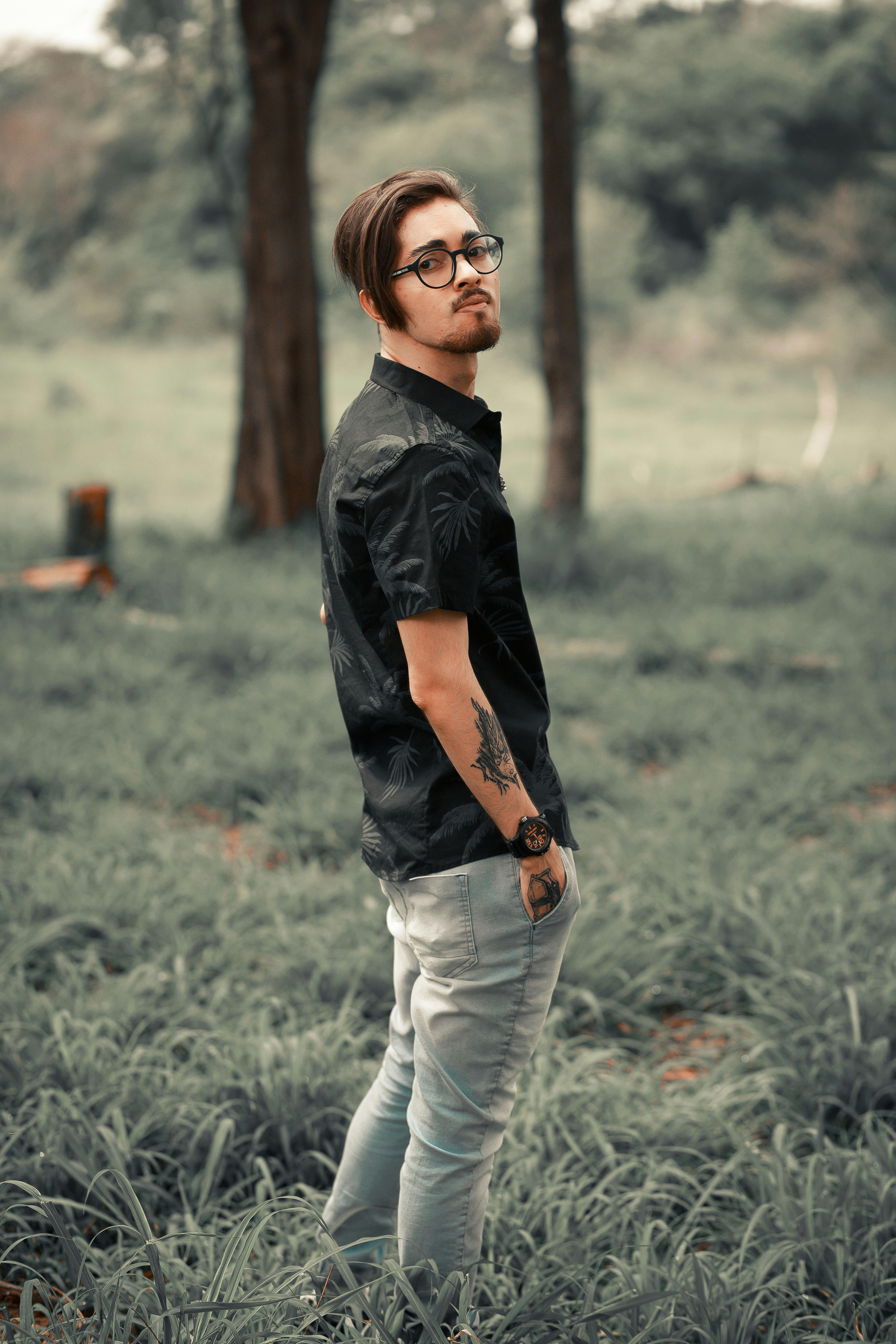 man in black polo and gray pants wearing eyeglasses with hand in pocket