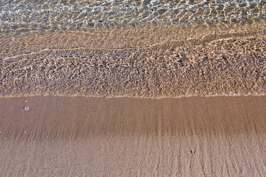 Close-up of a serene beach with gentle waves and golden sand, evoking a sense of tranquility.