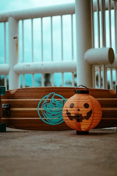 Orange Halloween lantern beside a skateboard on an outdoor promenade.
