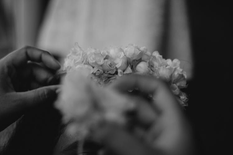 Grayscale Photo Of A Person's Hands Touching Flowers