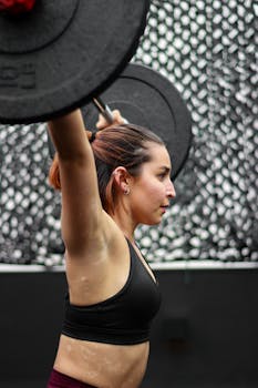 Focused woman lifting weights indoors, showcasing strength and determination.