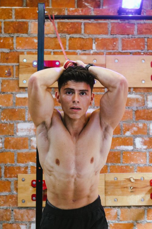 Free Muscular young man exercising indoors with a focus on fitness and strength. Urban gym setting. Stock Photo