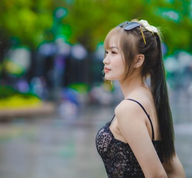 Portrait of an Asian woman in a black lace top outdoors, exuding elegance and fashion.