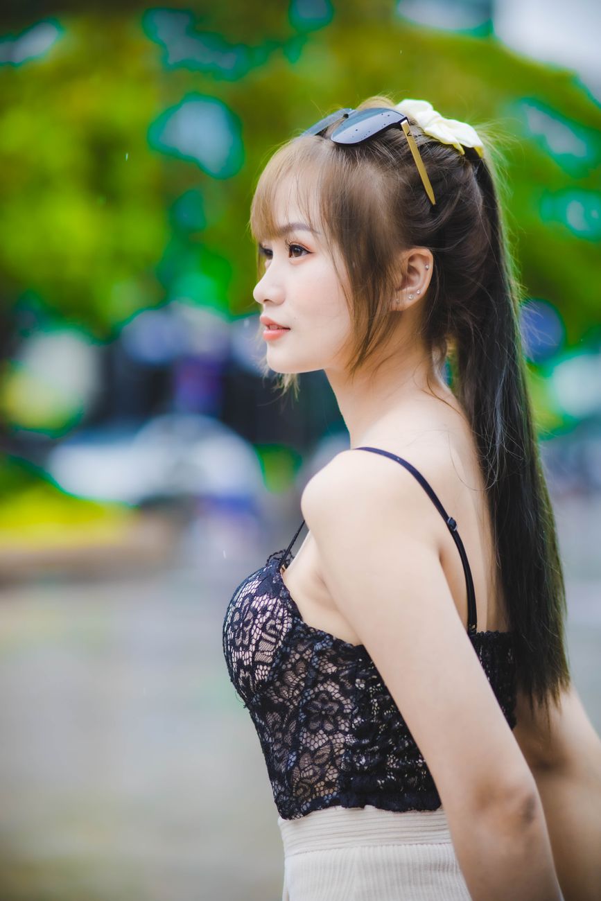 Fashionable young woman poses stylishly outdoors in a lace top.