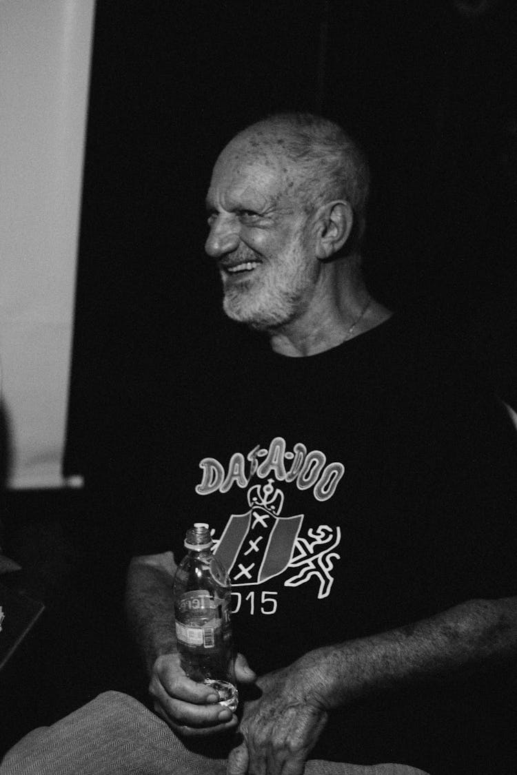 A Grayscale Photo Of An Elderly Man In A Black T-shirt