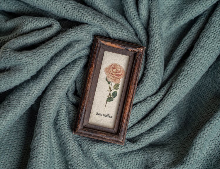 Painting Of Flower In An Old Wooden Frame On Green Knitted Fabric