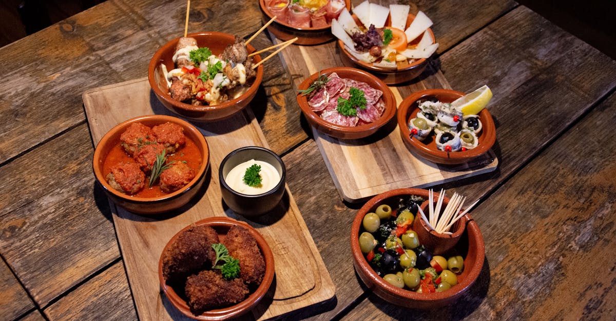 A wooden board filled with various types of colorful tapas, including olives, cheeses, and cured meats.