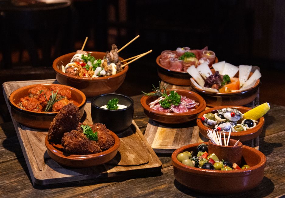 Camarero sirviendo tapas con carta en barra española