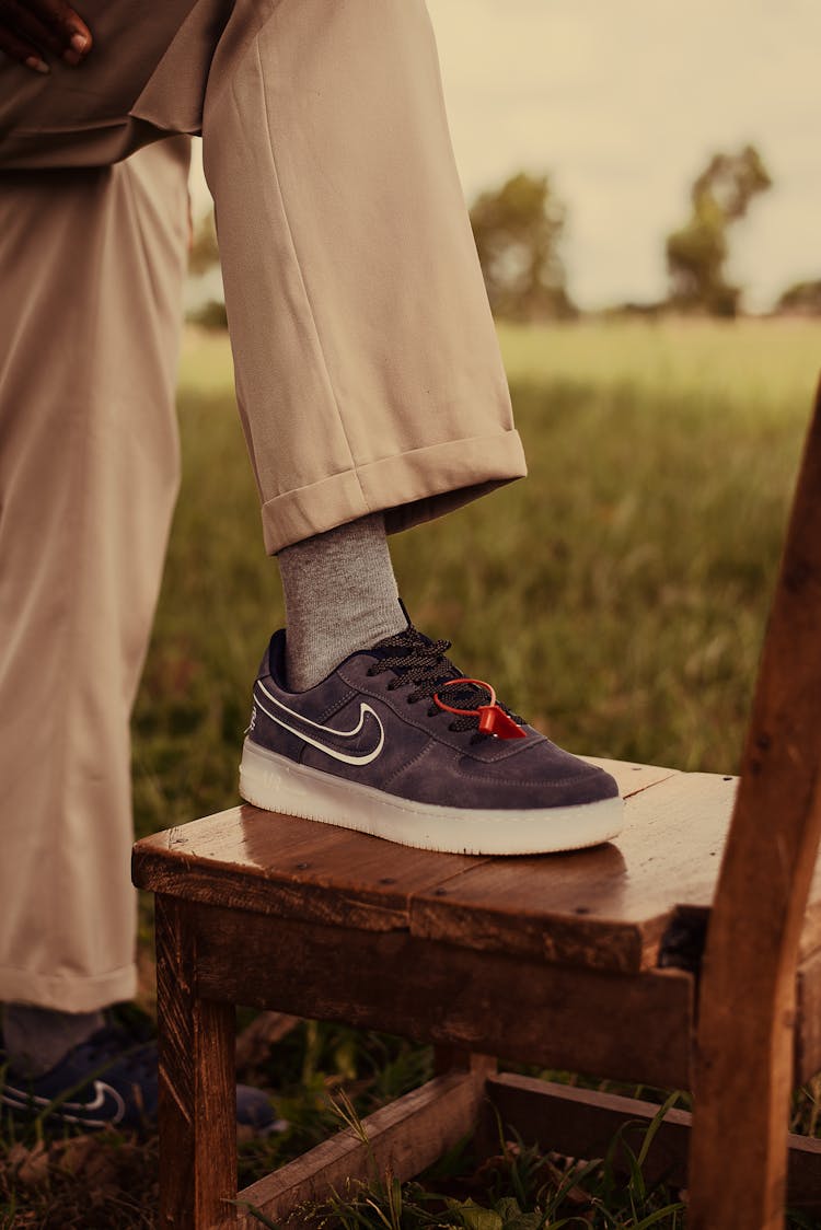 Man Leg In Sneakers In Field