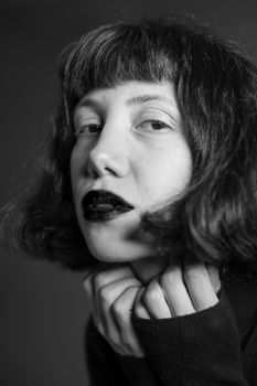 Elegant black and white portrait of a woman with bold makeup and thoughtful expression.