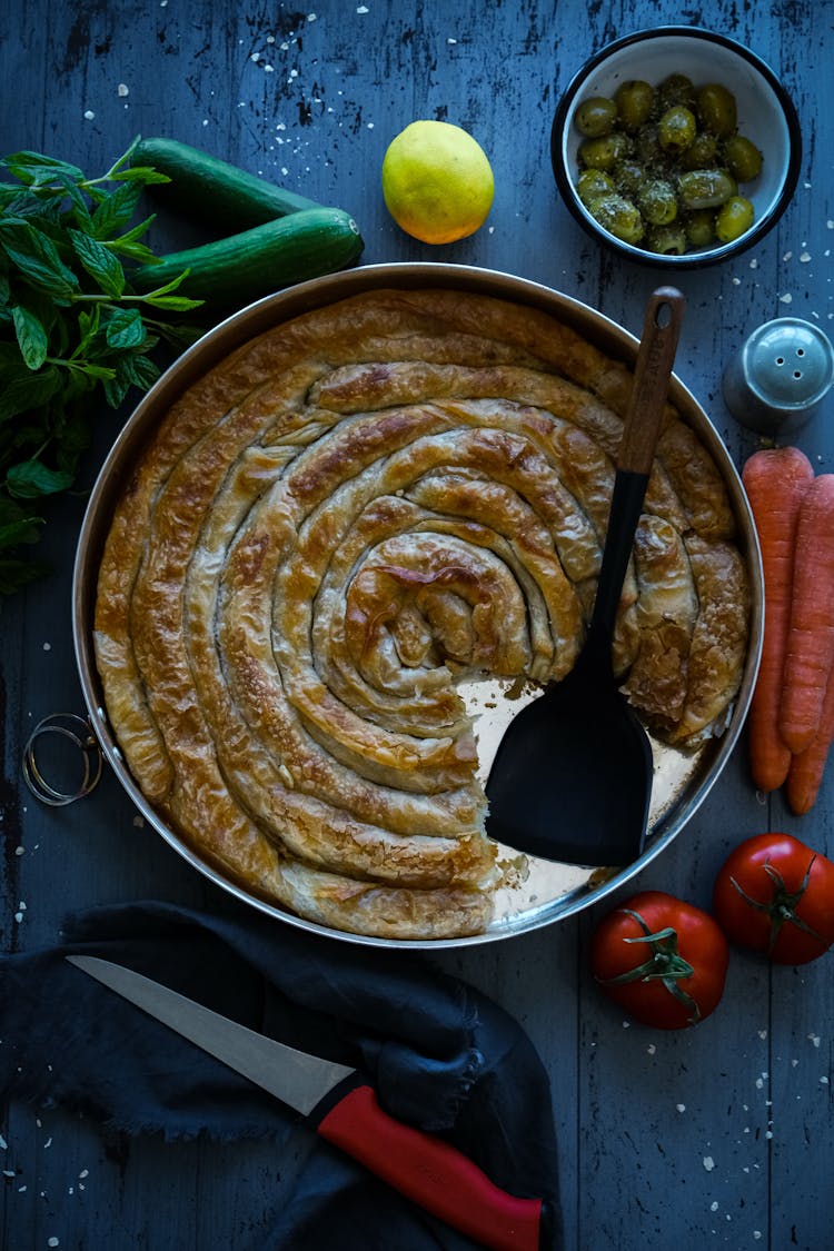 Top View Of A Savoury Pie And Vegetables On A Table