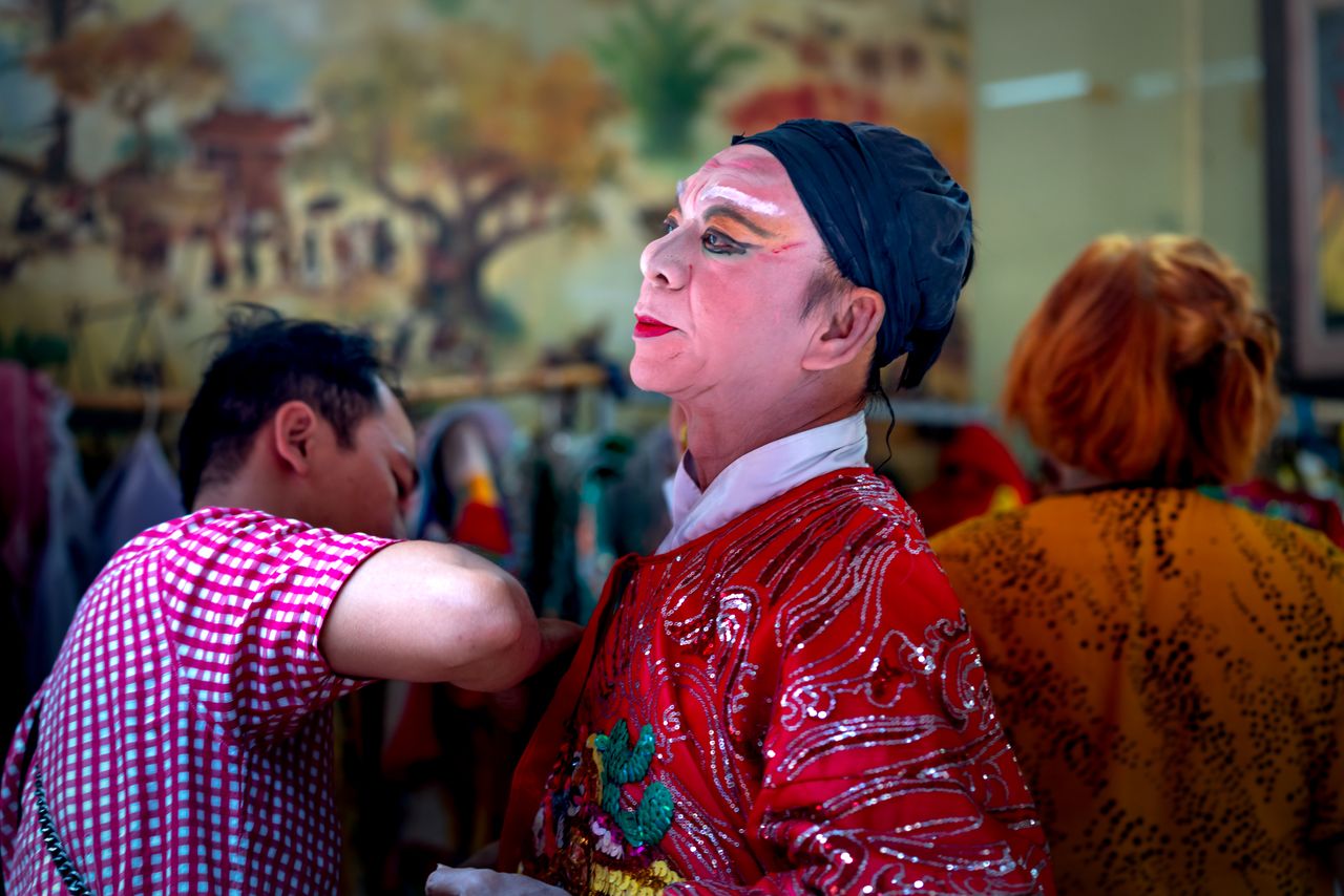 a performer preparing backstage in traditional chinese opera costume a