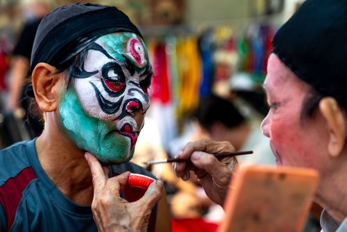 Free Close-up view of artists painting vibrant face masks at a festival. Stock Photo