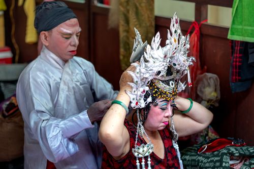 Free Asian performers applying makeup and costumes before a theatre show, highlighting cultural artistry. Stock Photo