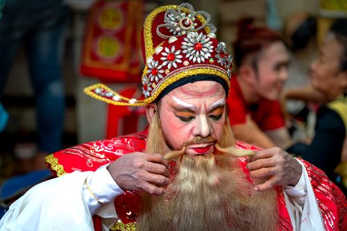 Free Close-up of a performer in traditional Asian festival attire adjusting costume. Stock Photo