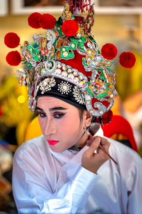Free Close-up of a performer applying makeup, showcasing traditional costume and elaborate headpiece. Stock Photo