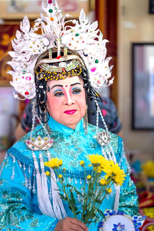 Free An elegant Asian woman in colorful traditional attire holding flowers, showcasing cultural beauty. Stock Photo
