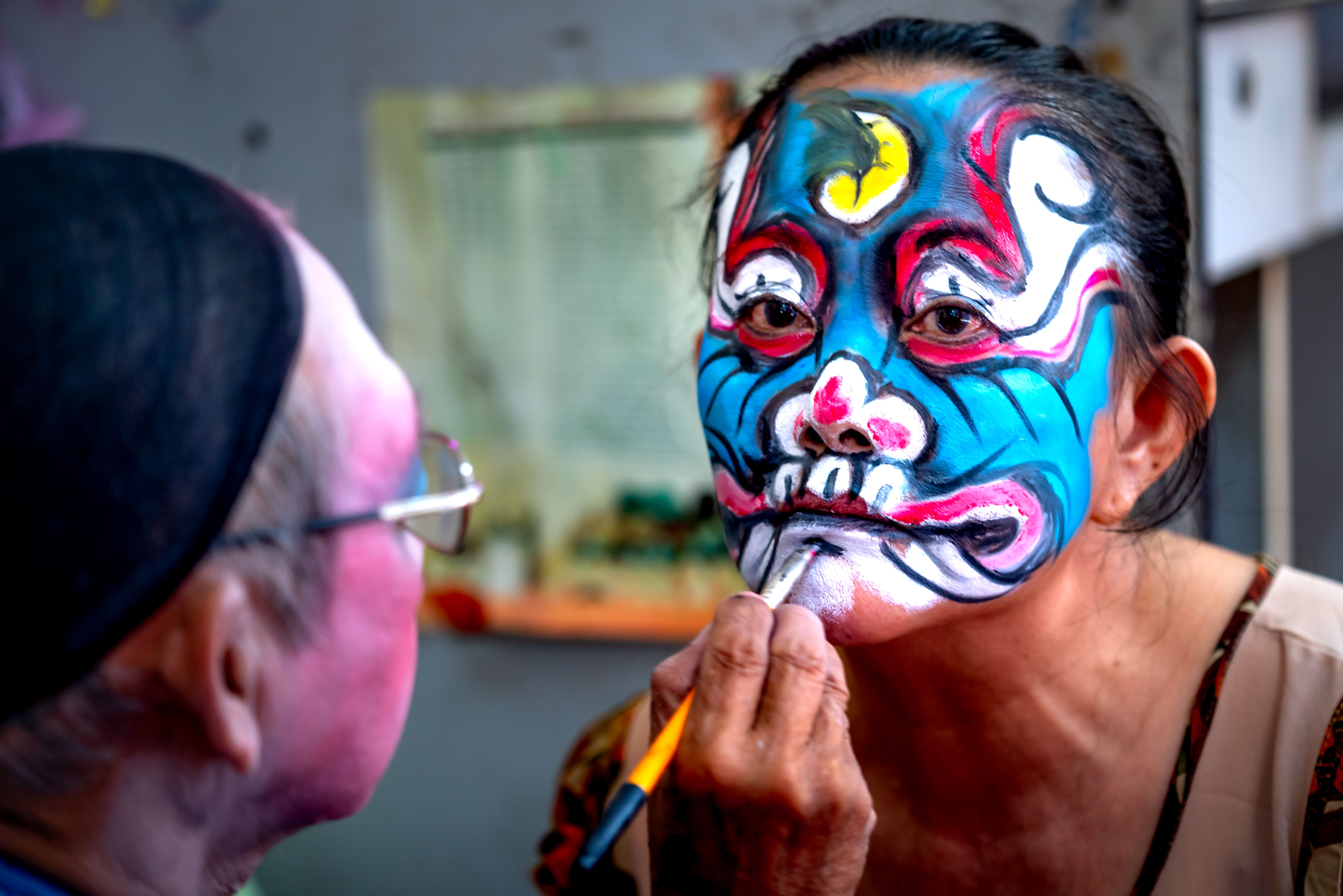 face painting artist cairo — Colorful face painting in progress at a lively cultural festival indoors.