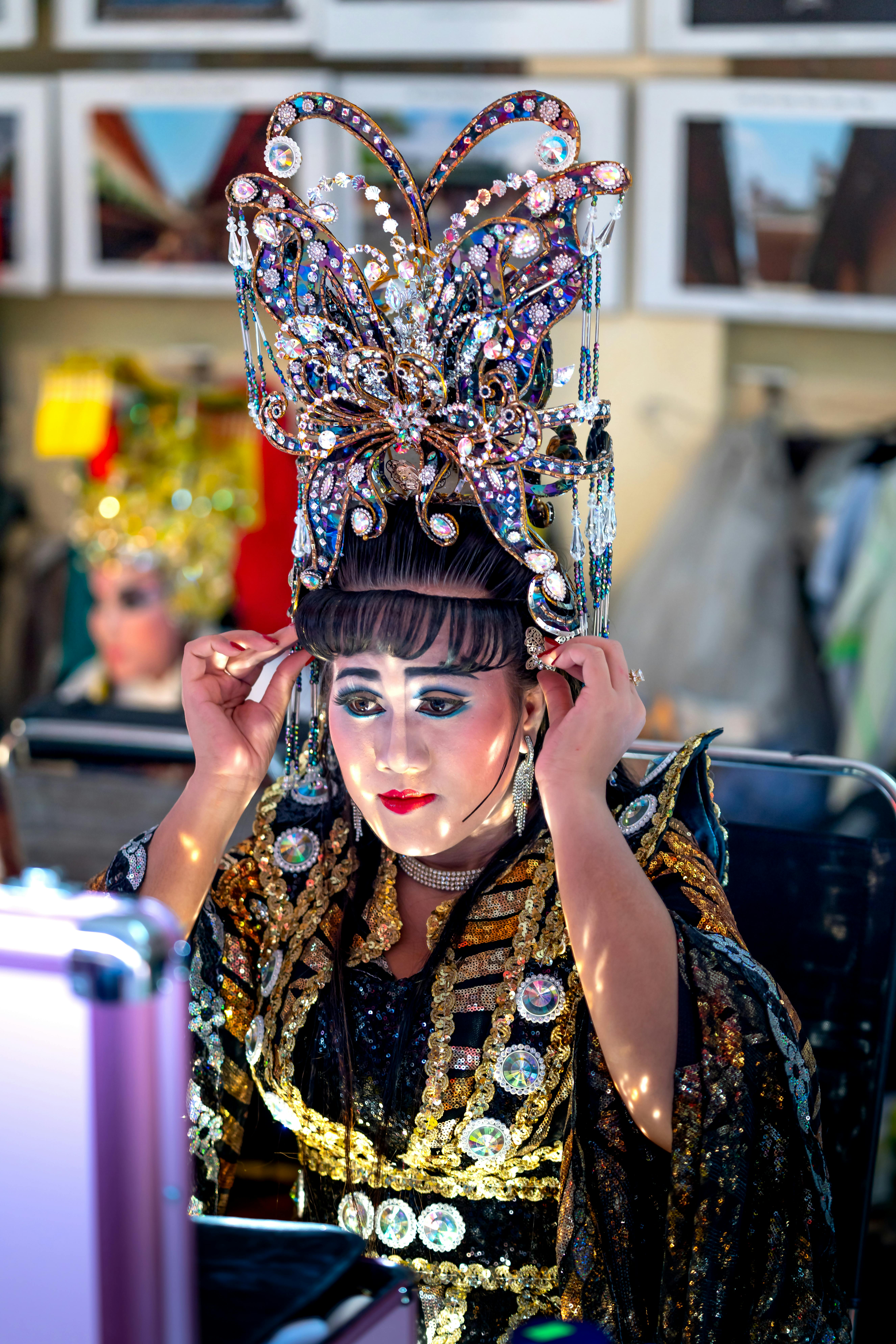 Free A performer backstage in an ornate costume and headdress prepares for a show. Stock Photo