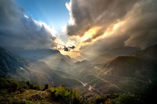 Free Breathtaking view of a mountain valley with dramatic clouds illuminated by the setting sun. Stock Photo