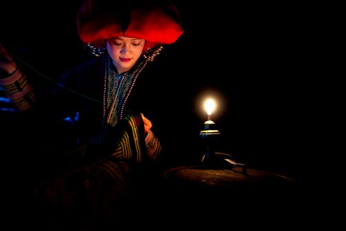 Free A woman in traditional attire sewing by candlelight, exuding cultural richness. Stock Photo