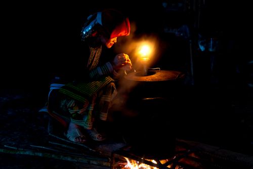 Free A woman in traditional clothing sitting by a pot with a lantern at night. Stock Photo