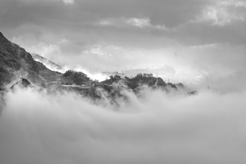Grayscale Photo of a Mountain Surrounded with Clouds