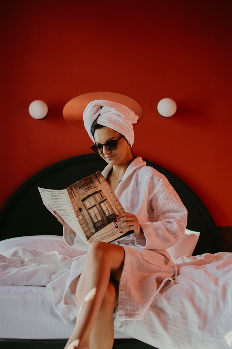 A Woman In A Bathrobe Reading A Magazine