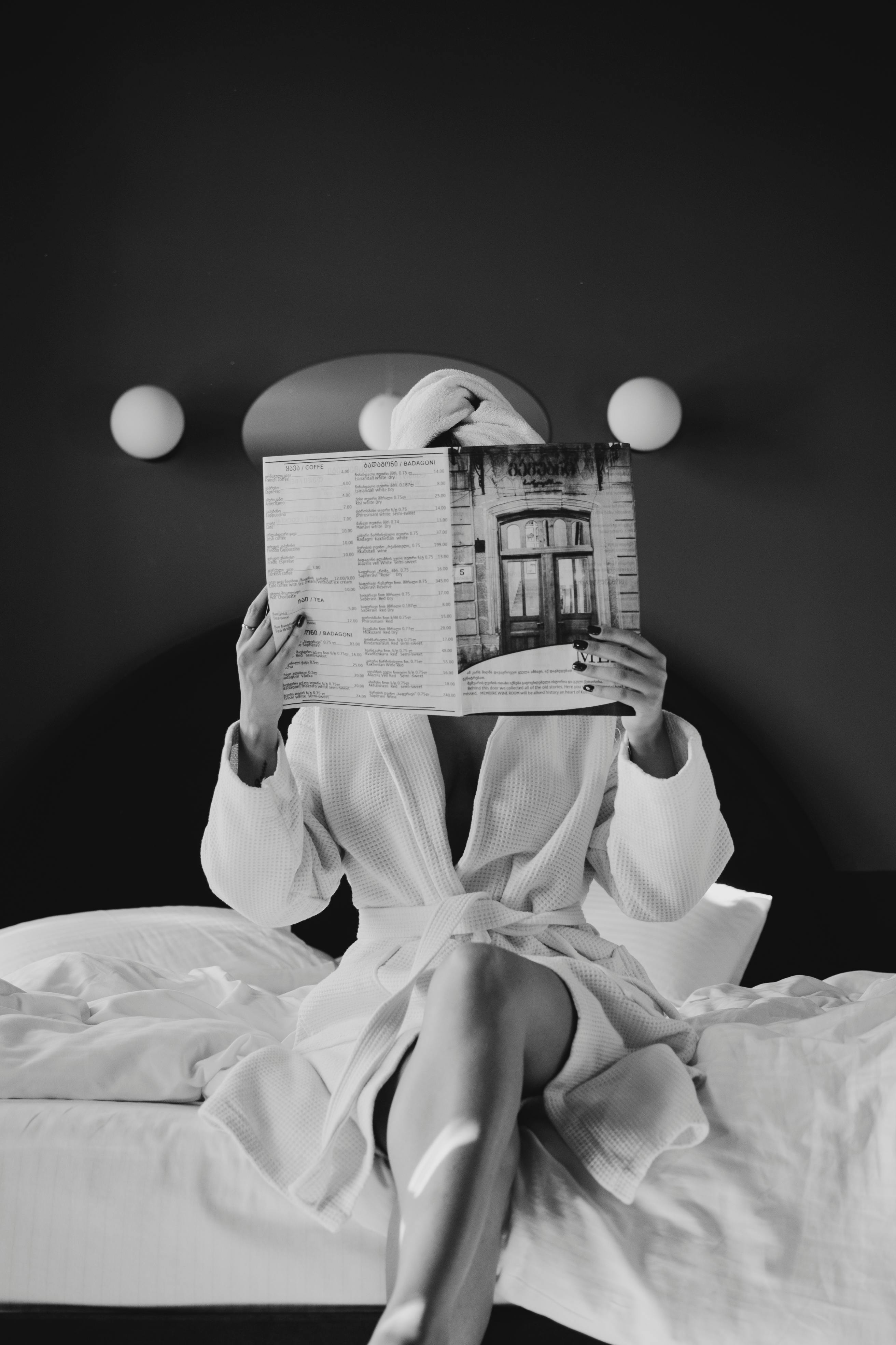 Woman Lying on Her Hotel Bed While Reading a Catalog · Free Stock Photo