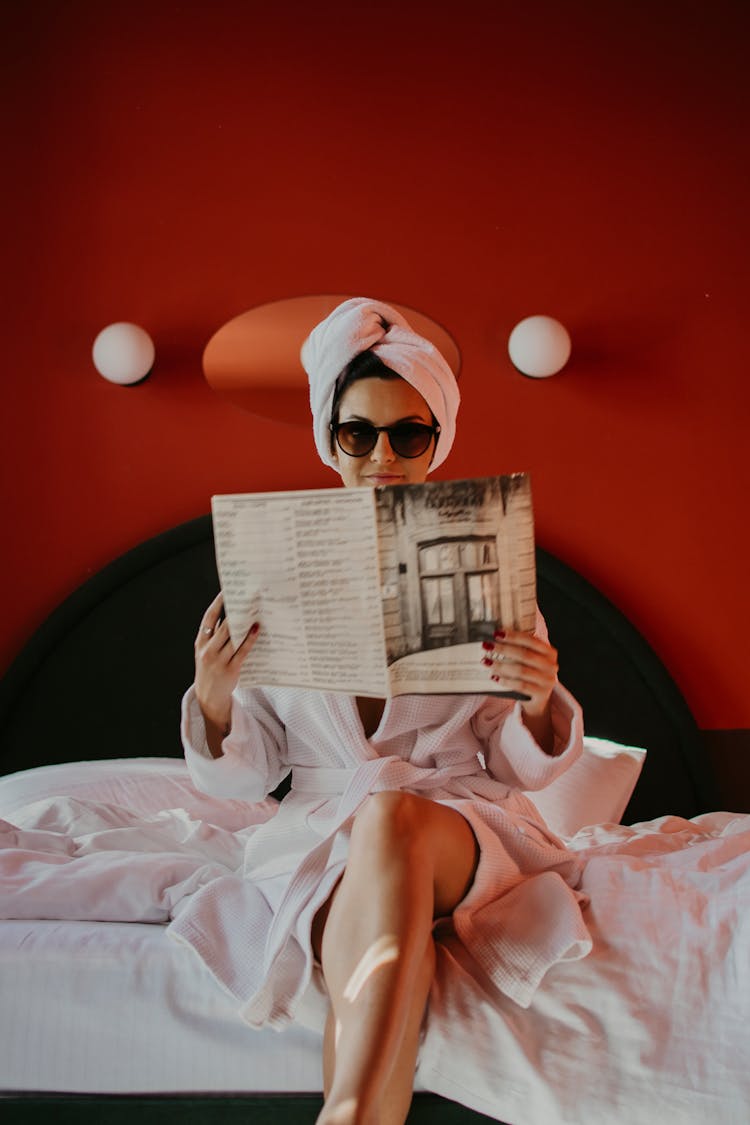 A Woman In A Robe Reading A Magazine