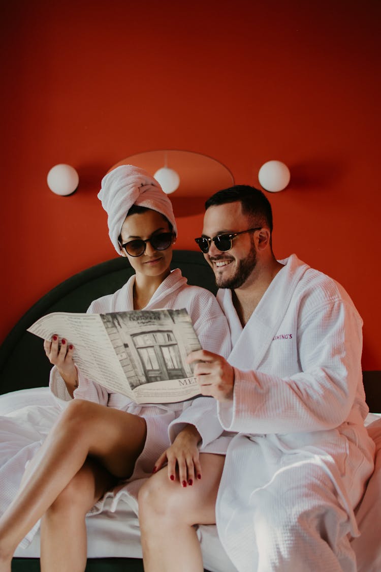 A Couple In Robes Reading A Magazine