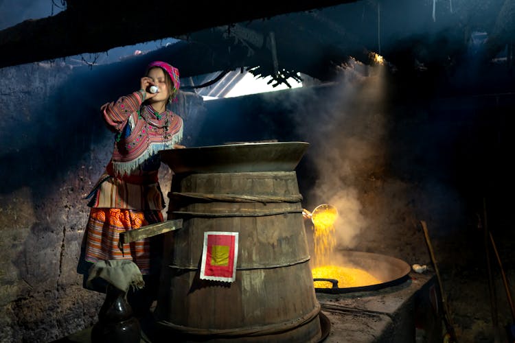 Woman In Traditional Clothes Cooking In Big Cauldron