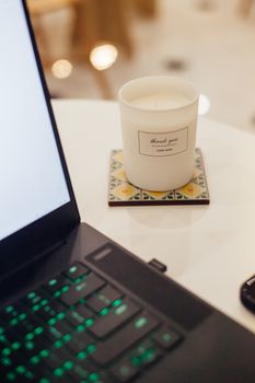 A workspace featuring a lit candle and laptop, creating a warm, inviting atmosphere.