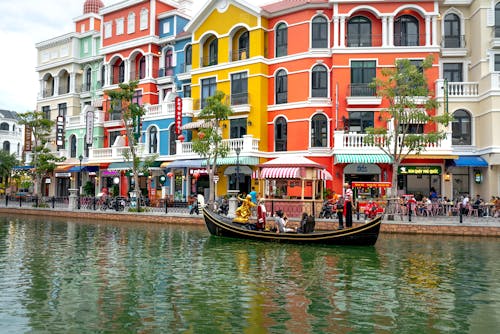 People Riding Boat on River Near Colorful Buildings