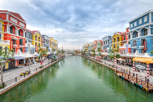 Body of Water in Between Colorful Buildings Under Cloudy Sky