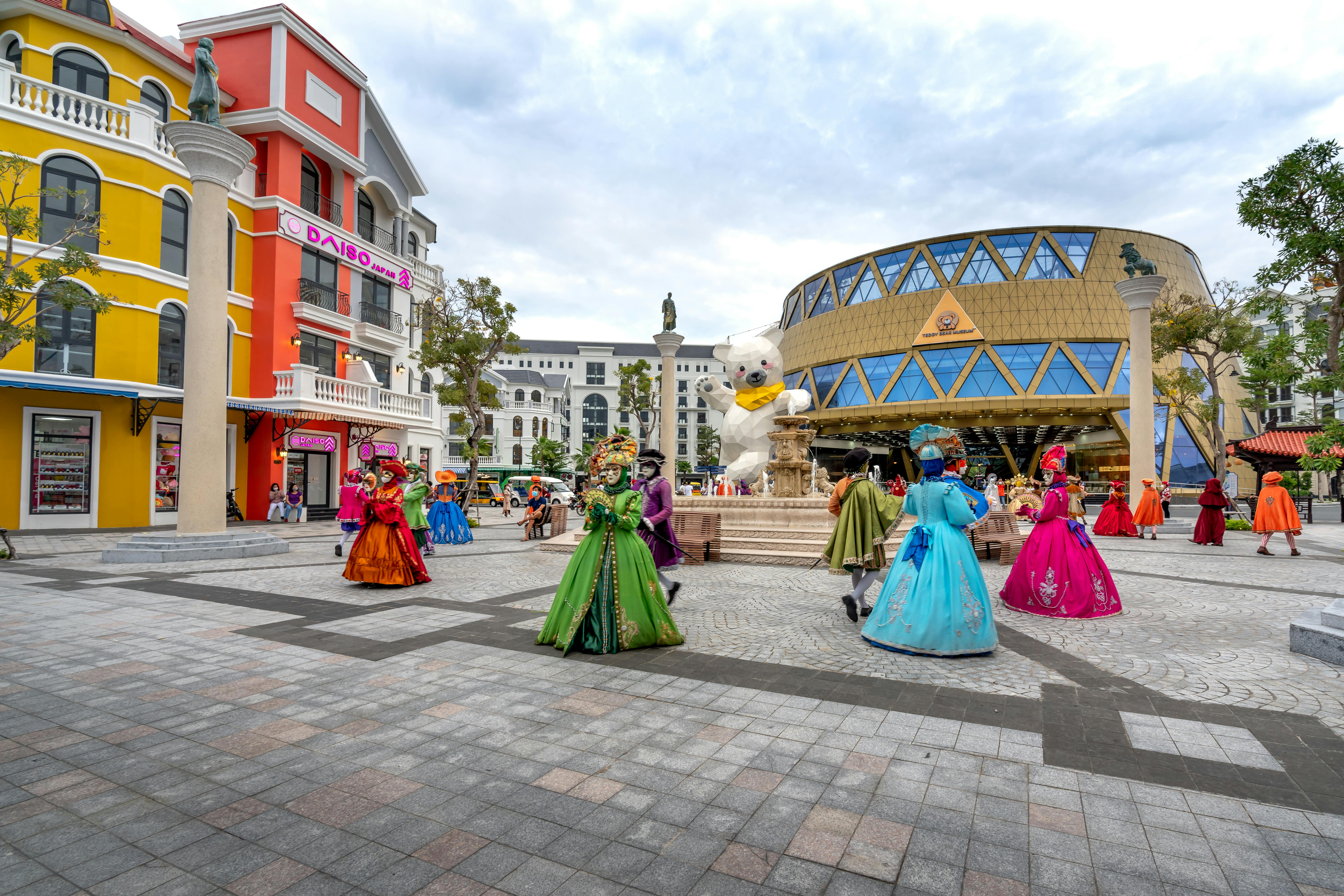 Free Vibrant street performers in colorful costumes entertaining a crowd in a lively city square. Stock Photo
