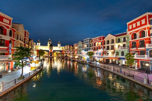 Free Vibrant canal scene with colorful buildings at night reflecting on water in Vietnam. Stock Photo
